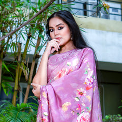Woman wearing a pink floral saree outdoors with greenery in the background