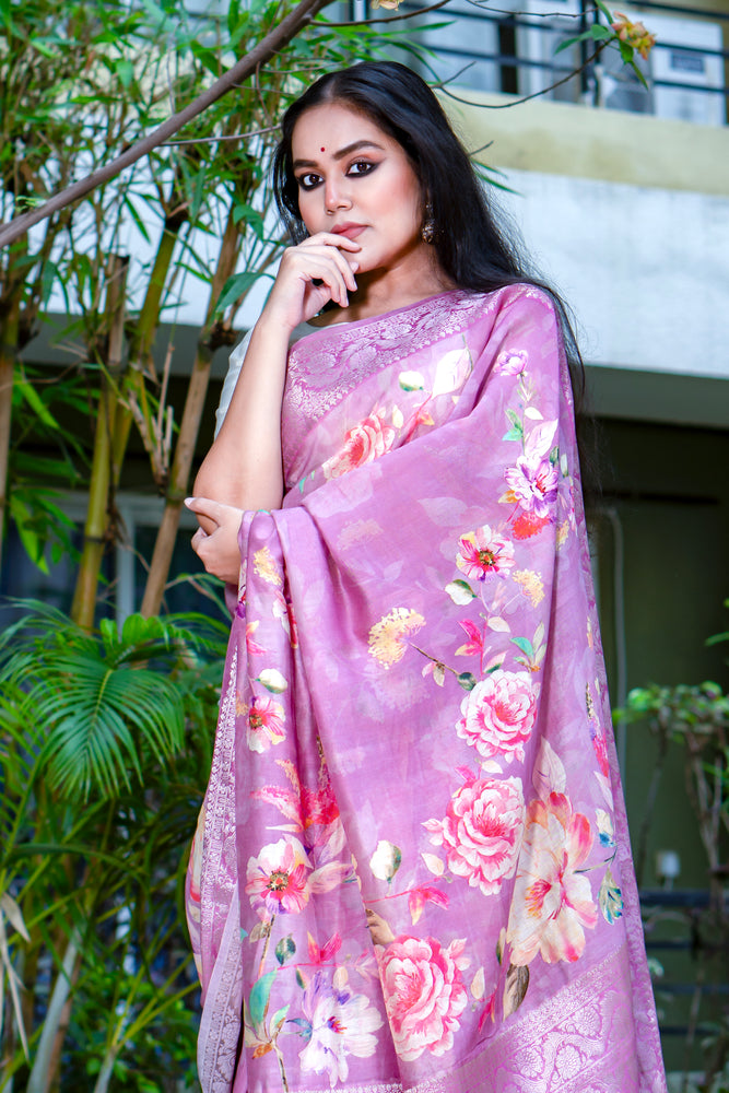Woman wearing a pink floral saree outdoors with greenery in the background