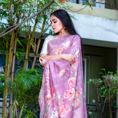 Woman wearing a pink saree with floral patterns outdoors.