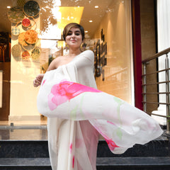 Woman in a white saree with pink accents standing in front of an Indiloom store.